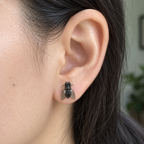 Buzzkill Large fly stud earring worn on an earlobe